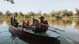 Family enjoying a peaceful day on a lake in a rowboat with life vests.